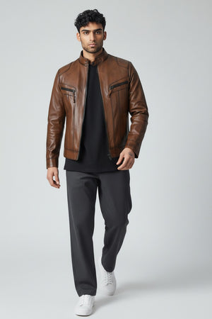Man wearing Metin2 brown leather jacket, black shirt, gray pants, and white shoes on a light gray background front view – Hilda Leather Turkey