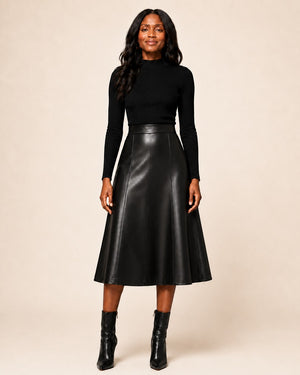 Model wearing a Hilda Leather black genuine lambskin midi skirt with an A-line silhouette and structured panel design.