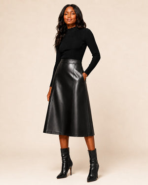 Model wearing a Hilda Leather black genuine lambskin midi skirt with an A-line silhouette and high-waisted fit.