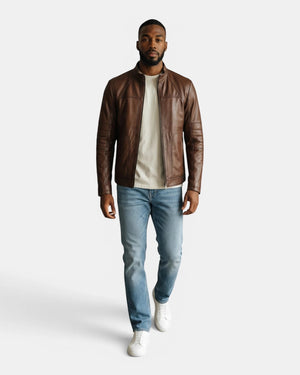 Model wearing a Hilda Leather brown napa lambskin sport jacket with a stand-up collar, jeans, and white sneakers.